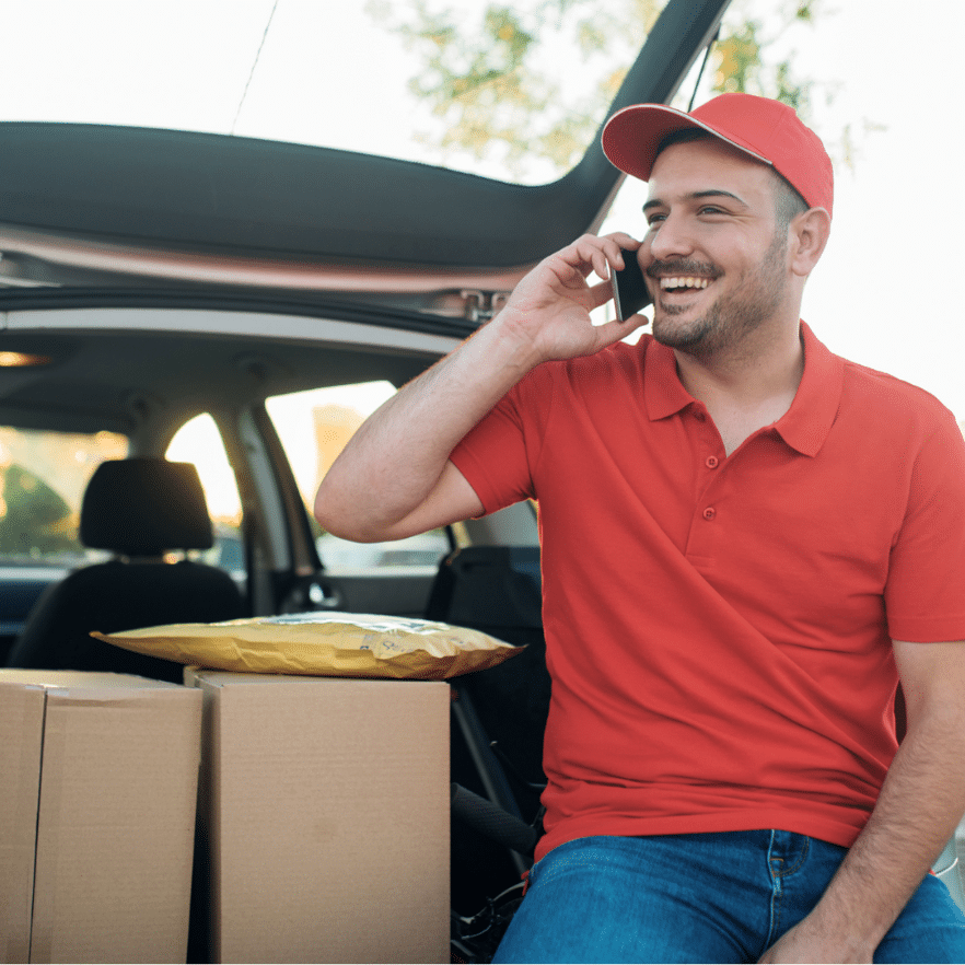 Happy delivery man talking to a customer on the phone Happy male customer service agent in a call center